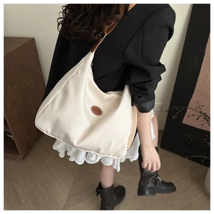 Détail du sac hobo en nylon crème avec bandoulière réglable et patch mode