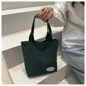 Detailed texture of dark green corduroy tote bag with white branded fanyissa label