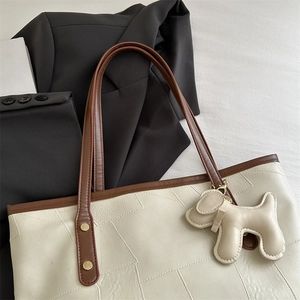 Sac fourre-tout beige à coutures géométriques avec pendentif chien et rivets dorés