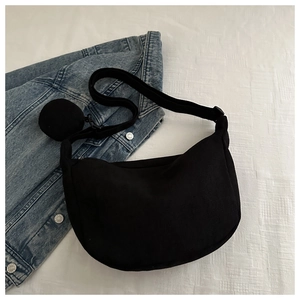 Detail of black corduroy crescent bag with textured stripes and round coin purse attachment