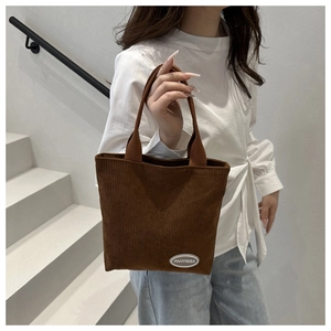 Detailed texture of brown corduroy tote bag showing vertical ribs and brand label