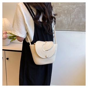Detail of off-white woven shoulder bag featuring spiral flap and pearl clasp closure