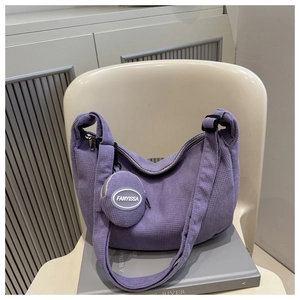 Detail of purple waffle-textured hobo bag with matching round coin purse and wide strap