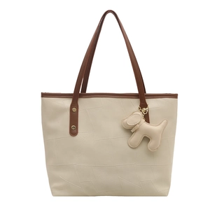 Grand sac cabas beige avec coutures géométriques, lanières marron et pendentif chien