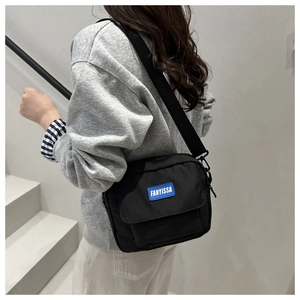 Detailed view of black nylon crossbody bag with adjustable strap worn by model