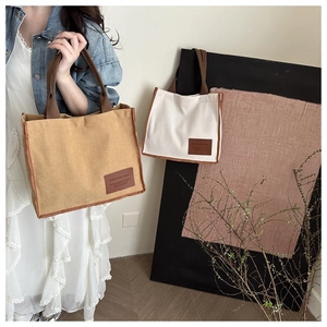 Detail of striped canvas tote bags with leather patch and contrasting handle straps