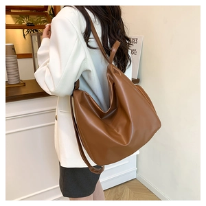 Brown pleated hobo shoulder bag styled with a white blazer in a cafe setting