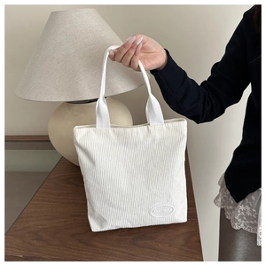 Detailed texture of white corduroy tote bag with minimalist FANYISSA label patch