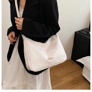 Détail du sac bandoulière blanc avec étiquette sur un mannequin élégant