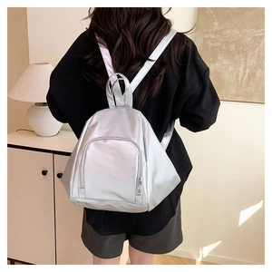 Silver pleated backpack shown on model featuring glossy finish and metallic texture