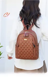 Detail of brown quilted leather backpack with gold rivets and metallic logo plate