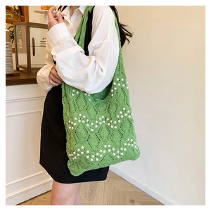 Detail of woven straw green tote bag with white pearl wave patterns and knit texture