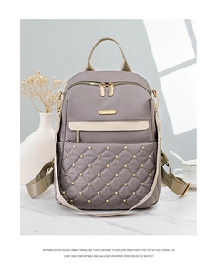 Detail of grey quilted backpack with golden rivets and premium metal zipper design
