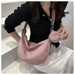Pink corduroy crescent shoulder bag with round coin purse detail on minimal background