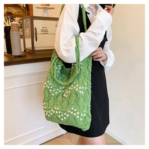 Detail of green knit crochet tote bag with pearl embellishments and wavy texture