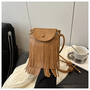 Détail d'un petit sac bandoulière marron en cuir avec de longues franges et rabat