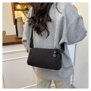 Dettaglio della borsa a tracolla in nylon nero con tracolla regolabile indossata da modella