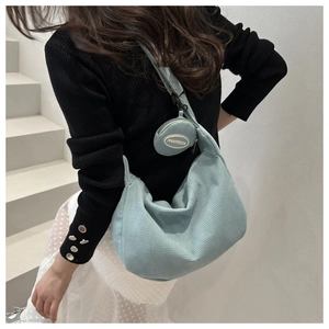 Detail of light blue corduroy waffle textured crossbody bag with a round mini pouch accessory