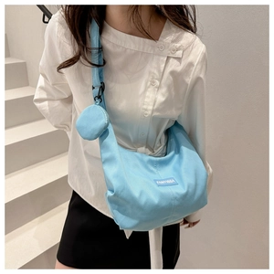 Detail of light blue nylon hobo bag with round coin purse and branded fabric label