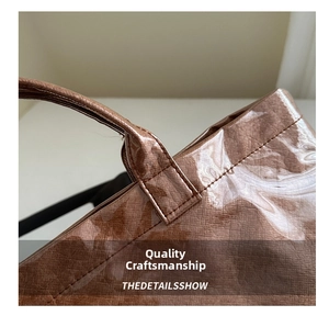 Close-up of brown woven handbag showing stitching detail and glossy waterproof finish