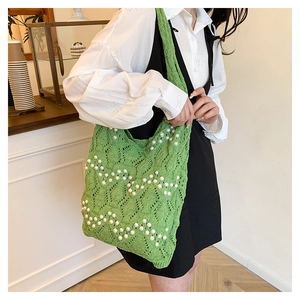 Detail of green knit tote bag with pearl accents and hollow diamond pattern