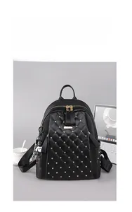 Detail of black quilted PU leather backpack featuring golden studs and bear charm