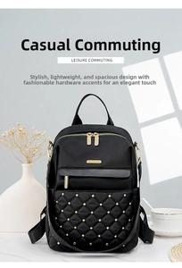 Detail of black quilted nylon backpack featuring golden studs and dual metal zippers