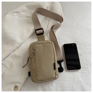 Macro view of khaki nylon crossbody bag showing the vertical zipper and small compact size