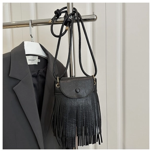 Détail du sac bandoulière en cuir noir avec de longues franges et bouton pression