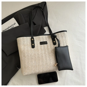 Détail du sac cabas en paille avec bordure en cuir noir, pochette assortie et logo métal