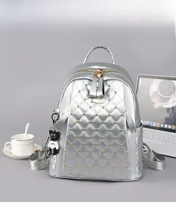 Detail of silver quilted backpack with gold studs and cute black bear charm accessory