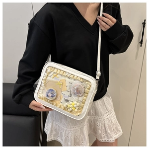 Detailed view of white Ita Bag with clear window and adjustable shoulder strap worn by model