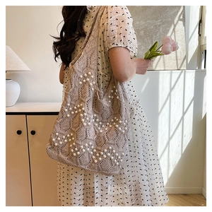 Detail view of woven knit tote bag featuring elegant white pearl bead embellishments
