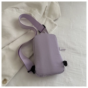 Close-up of lavender nylon chest bag with black plastic buckle on white grid fabric