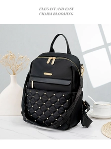 Detail of black quilted nylon backpack with gold studs and elegant metal zipper