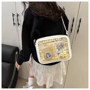 Detail of white cross-body ita bag with clear window and yellow lace trim decorations
