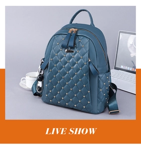 Detail view of teal quilted backpack with rivets and cute panda keychain near a laptop