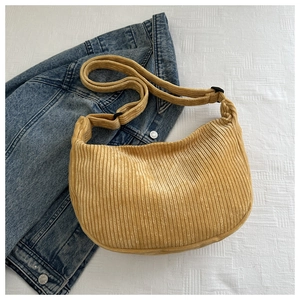 Detail of yellow corduroy crossbody bag texture on a blue denim jacket background