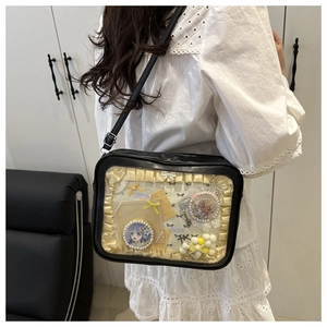 Detail of a black ita-bag with clear window displaying anime badges and lace decor