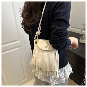 Détail d'un sac bandoulière blanc crème à franges avec texture cuir et sangle nouée