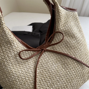 Straw tote bag with brown ribbon bow and leather trim for elegant summer fashion
