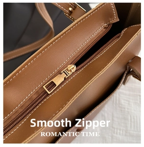 Detailed macro of smooth gold zipper and white stitching on brown leather tote bag