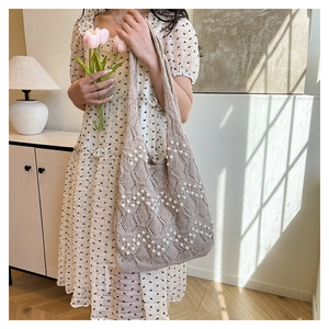 Detail shot of beige knit tote bag featuring hollow diamond patterns and pearl embellishments