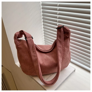 Macro shot of dusty rose corduroy texture on a half-moon hobo bag with wide straps