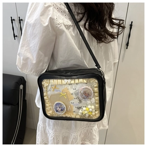 Detail of black PU leather ita bag with clear window and cream lace trim worn cross-body