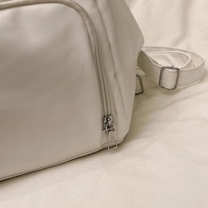 White minimalist leather crossbody bag with silver zipper and adjustable strap