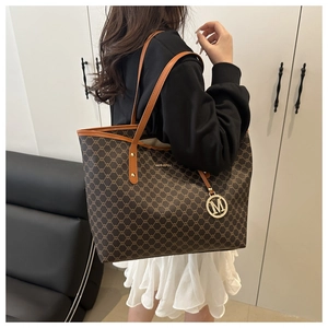 Detailansicht der großen Shopper-Tasche mit dunklem Monogramm-Muster am Modell