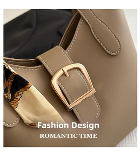 Detail of brown leather handbag featuring white stitching, gold buckle, and silk scarf wrap