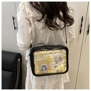 Detail of black ita bag with transparent window showing anime badges and yellow lace decoration