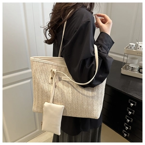 Detail of a beige woven straw tote bag featuring a mini pouch and side logo emblem